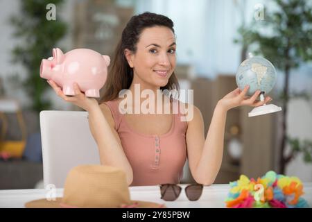 femme heureuse avec tirelire et concept de globe Banque D'Images