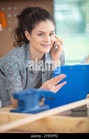 apprentie femme tenant une planchette à pince dans l'atelier Banque D'Images