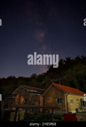 Capturée à Yeongwol, dans la province de Gangwon, cette photo montre la voie lactée qui s'étend à travers le ciel nocturne au-dessus d'une petite maison tranquille. Banque D'Images