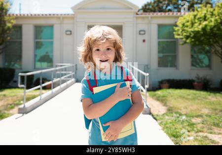 Enfant avec sacs à dos debout dans le parc près de l'école. Élèves avec des livres et des sacs à dos à l'extérieur. Enfant avec sac à dos pour aller à l'école. Éducation des enfants Banque D'Images