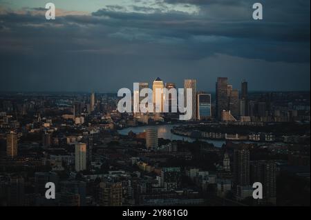Un Canada Square et d'autres bâtiments dans les Docklands de Londres éclairés par un coucher de soleil et situés dans une vue large de l'est de Londres photographié depuis la ville de Londres Banque D'Images