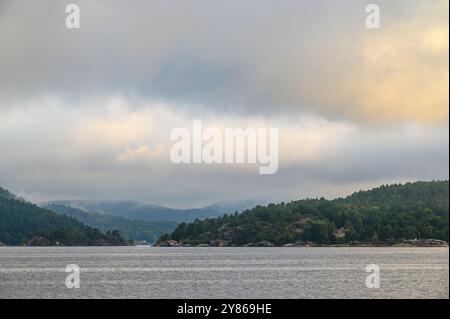 Vue de l'île de Buholmen tôt le matin avec de faibles nuages et brume sur la mer aux îles Gumoy et Fluer dans l'archipel de Kragero, Telemark Norvège. Banque D'Images