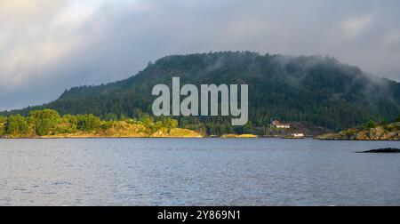 Lever de soleil et lever la brume et disperser les nuages dans l'archipel de Kragero dans le comté de Telemark, Norvège. Banque D'Images