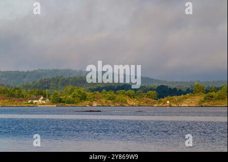 Lever de soleil et lever la brume et disperser les nuages avec la maison d'été en bord de mer dans l'archipel de Kragero dans le comté de Telemark, Norvège. Banque D'Images