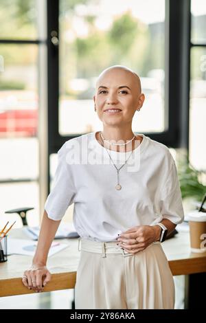 Une jeune femme chauve élégante se tient en toute confiance dans un bureau contemporain, souriant chaleureusement. Banque D'Images