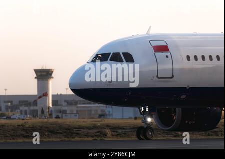 L'avion roule sur la piste au coucher du soleil avec les pilotes visibles dans le cockpit Banque D'Images