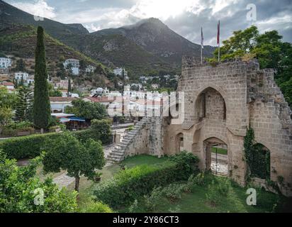 Ruines médiévales de l'abbaye de Bellapais surplombant le pittoresque village de Bellapais dans les montagnes Kyrenia, Chypre Banque D'Images