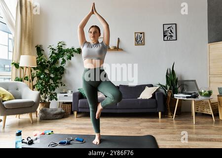 Une jeune femme sportive pratique le yoga dans son salon élégant, améliorant sa force et son équilibre. Banque D'Images