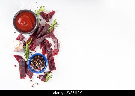 Snack de viande séchée, viande de bœuf séchée. Collations à la viande de bœuf saine, avec sauce et épices sur le plateau de service, espace de copie Banque D'Images