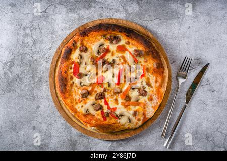 Pizza avec paprika et rôti de bœuf sur planche à découper sur table en pierre Banque D'Images