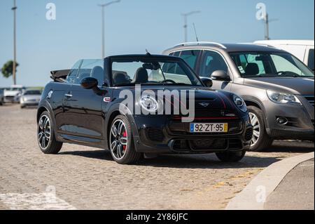 Porto, Portugal - 13 septembre 2024 : Un élégant cabriolet noir est garé sous un ciel dégagé à côté du front de mer. Banque D'Images