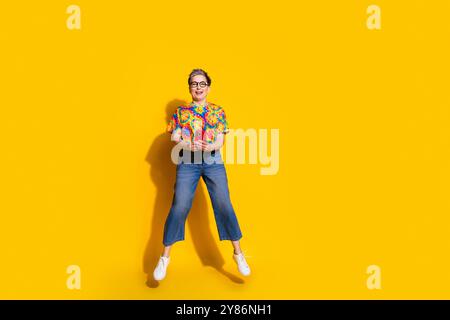 Photo en taille réelle de belle dame âgée tenir téléphone saut d'espace vide porter t-shirt isolé sur fond de couleur jaune Banque D'Images