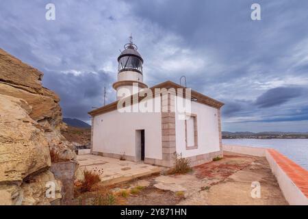 Phare de Cala Nans sur des rochers sous ciel nuageux avec une mer orageuse en arrière-plan, Espagne, Catalogne Banque D'Images