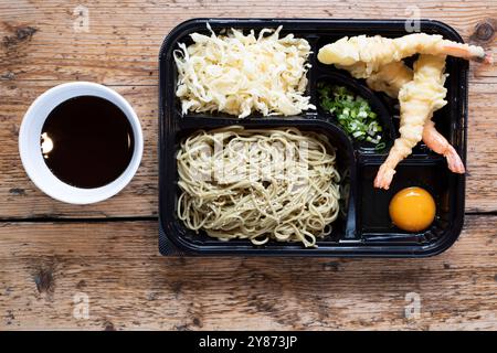 Boîte à bento aux crevettes royales panées au tempura chinois, servie avec des nouilles, des légumes marinés et une sauce aux œufs crus Banque D'Images