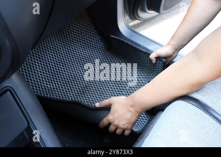 Homme prenant tapis de voiture en caoutchouc gris de l'auto, gros plan Banque D'Images