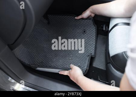 Homme prenant tapis de voiture en caoutchouc gris de l'auto, gros plan Banque D'Images