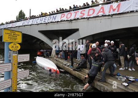 Potsdam, Allemagne. 03 Oct, 2024. Les assistants sortent de l'eau les participants d'une équipe commerciale de Potsdam au 3e Potsdam Canoe Sprint sur l'Alte Fahrt après que leur bateau a renversé. Crédit : Michael Bahlo/dpa/Alamy Live News Banque D'Images