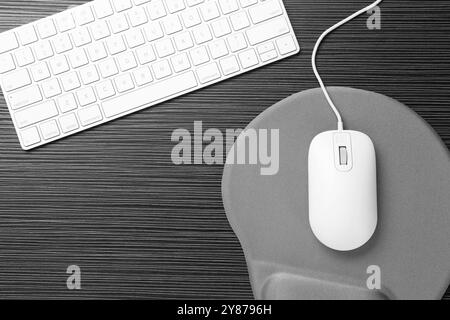 Souris d'ordinateur, tapis de souris et clavier sur table en bois noir, plat Banque D'Images