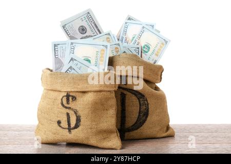Billets de banque en dollars dans des sacs sur une table en bois sur fond blanc Banque D'Images