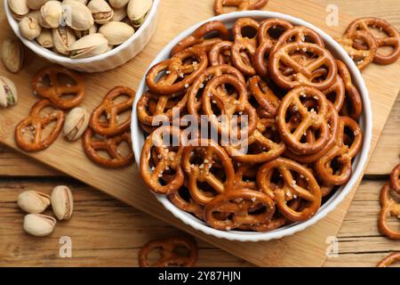 Délicieux bretzel craquelins et pistaches sur table en bois, plat Banque D'Images