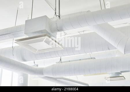 Plan d'arrière-plan d'un système de ventilation industriel dans une usine de fabrication pharmaceutique. Tuyaux d'évent peints en blanc avec maille d'échappement sous plafond fournissant l'échange d'air, espace de copie Banque D'Images