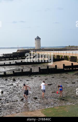 Enfants jouant dans la boue et chassant des choses pendant la marée basse à Brightlingsea Essex Angleterre Banque D'Images