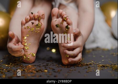 confettis dorés sur les pieds de la fille. célébration d'anniversaire. Banque D'Images