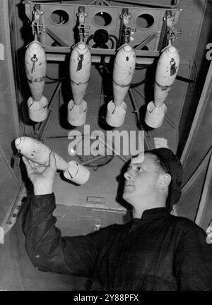 Ces bombes, qu'un membre du personnel au sol de la Royal Australian Air Force glisse dans les casiers sous une aile d'une machine Avro Anson à Laverton, certains de ceux qui ont été largués sur la cible d'entraînement remorquée par le destroyer Vampire au large du cap Schanck cet après-midi lors d'un entraînement à grande échelle. 28 novembre 1938 Banque D'Images