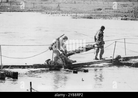 Blessé Yank transporté à travers Roer -- les porteurs de brancards portent un soldat américain blessé sur le corps d'un ami mort alors qu'ils négocient un pont temporaire sur la rivière Roer en Allemagne. Le soldat a été blessé et son copain tué lors de la traversée de la barrière allemande par les forces du yank, à la suite de quoi les Américains ont balayé vers le Rhin. 2 mars 1945. (Photo d'Associated Press photo). Banque D'Images