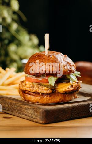 Délicieux burger de porc effiloché avec laitue fraîche et fromage fondu servi avec des frites à bord Banque D'Images