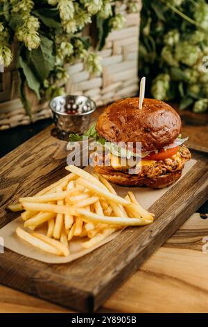 Délicieux burger de porc effiloché avec laitue fraîche et fromage fondu servi avec des frites à bord Banque D'Images