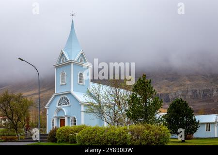 L'église bleue de Seydisfjordur (Seydisfjardarkirkja), vue extérieure de la façade bleu vif du bâtiment avec une végétation verte autour, Islande. Banque D'Images