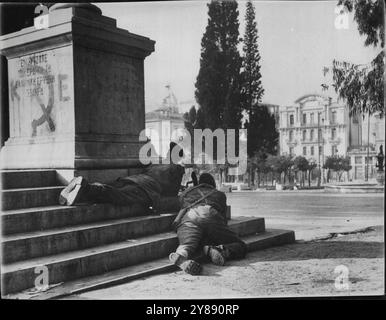 Parachutistes sur la place de la Constitution d'Athènes -- les parachutistes qui combattent les forces Elas à Athènes, en Grèce, au début du mois de décembre, se cachent derrière un poste sur la place de la Constitution alors qu'ils se déplacent sur le bâtiment du KKE (communiste). 16 décembre 1944. (Photo d'Associated Press photo). Banque D'Images