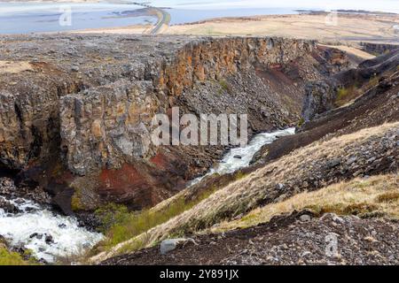 Vallée de la rivière Hengifossa à Fljotsdalshreppur, dans l'est de l'Islande avec des formations rocheuses rouges et brunes, des falaises et le lac glaciaire Lagarfljot en arrière-plan. Banque D'Images