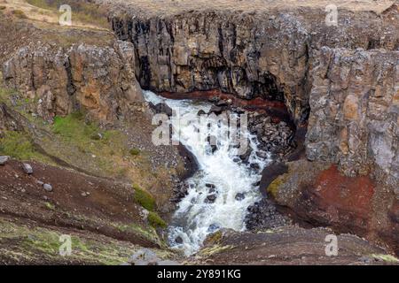 Vallée de la rivière Hengifossa à Fljotsdalshreppur, dans l'est de l'Islande avec des formations rocheuses rouges et brunes et rivière sauvage. Banque D'Images