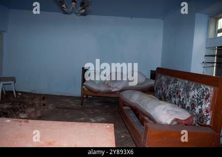 Chambre abandonnée avec lits non faits et décor rustique. Banque D'Images