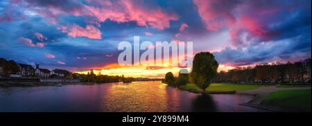 Coucher de soleil spectaculaire sur la rivière Neckar à Heidelberg, Allemagne. Ciel coloré avec des nuages roses et bleus et la lumière dorée du soleil reflétée dans l'eau à Banque D'Images