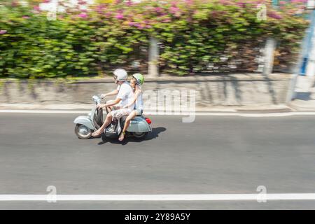 Homme et fille monte un scooter vintage vert menthe sur une journée ensoleillée devant un mur beige avec des plantes en pot sorrento italie Banque D'Images