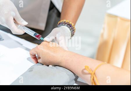 Gros plan de la main de l'infirmière, du médecin ou du technologue médical dans des gants blancs prélevant un échantillon de sang d'un patient à l'hôpital. Banque D'Images