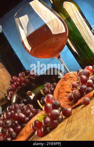 Verre et bouteille de vin sur la table avec des raisins au premier plan Banque D'Images