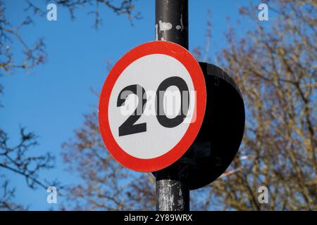 Panneau routier de limitation de vitesse de 20 km/h le long d'une route locale, sur fond flou à Saffron Walden, Essex, Royaume-Uni. Banque D'Images