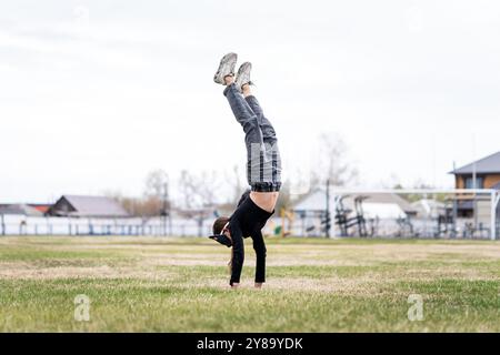 Adolescente avec masque de chat et gants faisant Quadrobics. Une fille dans un masque de chat saute comme un chat. l'athlète se tient sur ses mains Banque D'Images