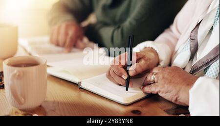 Bible, couple et mains écriture de femme avec prière, étude et éducation spirituelle par table. Prier, apprendre et testament chrétien avec adoration Banque D'Images