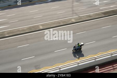Motocyclette de livraison circulant sur route, avec indication de mouvement flou dans les environs. Banque D'Images