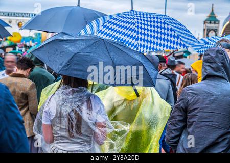 Mit Regenschirm und Regenponcho auf die Wiesn, München, septembre 2024 Deutschland, München, 28. Septembre 2024, Wiesnbummel im Regen, Wiesnbesucher mit Regenschirm und Regenponcho am Samstagabend auf der Theresienwiese unterwegs, Wochenende, Symbolfoto, nasskaltes Regenwetter, bayerisch, Oktoberfest 2024, Volksfest, Bayern, *** avec parapluie et poncho de pluie sur la Wiesn, Munich, septembre 2024 Allemagne, Munich, septembre 28, 2024, Wiesnbummel sous la pluie, Wiesn visiteurs avec parapluie et poncho de pluie le samedi soir sur la Theresienwiese, week-end, photo symbolique, temps pluvieux humide et froid, Banque D'Images