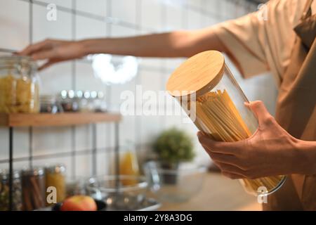 Gros plan image d'un homme tenant un pot en verre rempli de spaghettis crus. Concept de personnes, de nourriture et de style de vie Banque D'Images