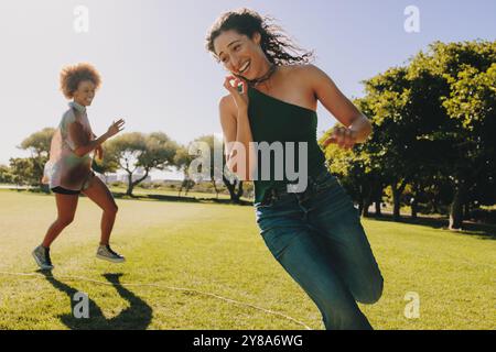 Deux jeunes femmes engagées dans des activités de plein air dynamiques et amusantes, profitant de la liberté d'une journée ensoleillée dans le parc. Des moments vivants et joyeux capturés. Banque D'Images