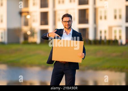Beau homme d'affaires tenant le tableau vide et pointant le doigt. Homme montrant un panneau vierge avec espace de copie. Idée et offre. Votre publicité. Vide Banque D'Images