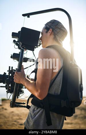 Vidéaste, homme et caméra vidéo en extérieur pour film, production professionnelle ou documentaire de voyage. Caméraman, enregistrement et tournage dans la nature avec Banque D'Images