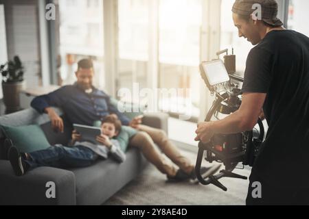 Vidéaste, professionnel et homme avec caméra à la maison pour filmer famille, père et enfant sur tablette. Caméraman, tournage et enregistrement vidéo avec Banque D'Images